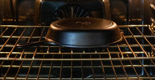 A Lodge cast iron skillet cools in the oven after it&#039;s been seasoned